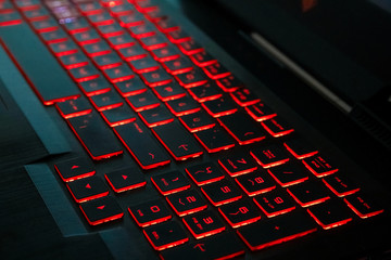 Red backlight on a modern keyboard of gaming laptop in the dark