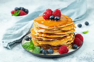Close-up delicious pancakes, with fresh blueberries, raspberry's and honey on a light background