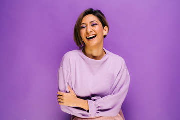 Amazing young woman laughing portraits in studio - Isolated over colorful bold purple background