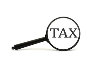  tax word through magnifying glass. Isolated on white. Business concept.