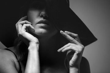 Beautiful portrait of a woman in a big hat. Studio. Close-up. The photo is black and white.