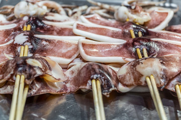 Traditional Chinese sea food calamary on wooden skewers on a big large metal pan