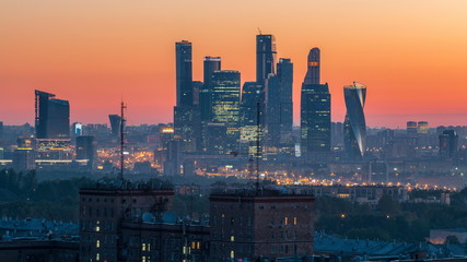 Fototapeta na wymiar View from top of cityscape night to day timelapse, residential buildings, park areas, group of Moscow City skyscrapers in distance, horizon, morning mist before sunrise, Moscow, Russia
