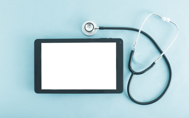 Computer tablet with a white screen on a blue background and a stethoscope. The concept of introducing electronic tablets and gadgets into medicine, a patient s electronic card, background, copy space