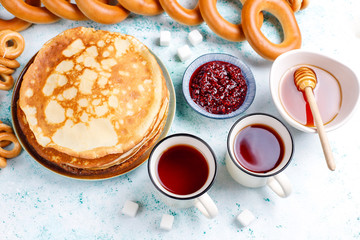 Shrovetide Maslenitsa festival meal. Russian pancake blini with raspberry jam, honey, fresh cream and red caviar,sugar cubes,cottage cheese,bubliks on light background