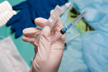 Doctor's hand holds a syringe. Hand with a syringe on a background of medical instruments.