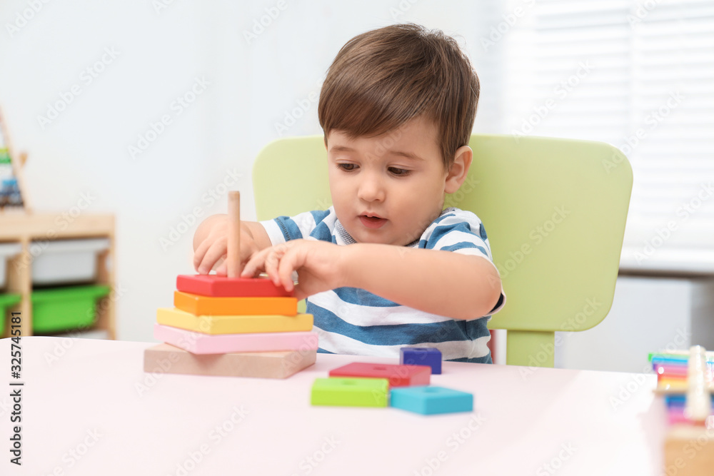 Wall mural Little child playing with toy pyramid at table