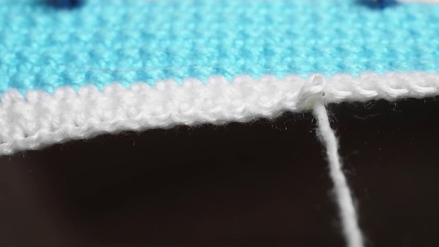 Blue-and-white knitted thing is unfurling. Slowmo Extreme Close-up View.