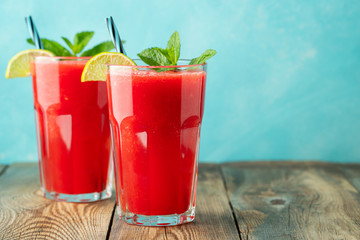 Watermelon slushie with lime and mint, summer refreshing drink in tall glasses on a light blue background. Sweet cold smoothie with copy space