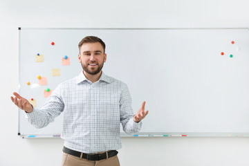 Portrait of young teacher near whiteboard in classroom. Space for text