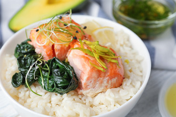 Tasty salmon with rice and spinach on white wooden table, closeup