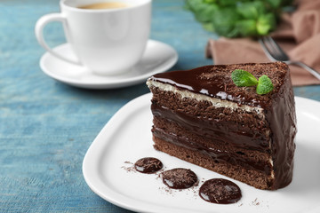 Delicious chocolate cake with mint on light blue wooden table, closeup