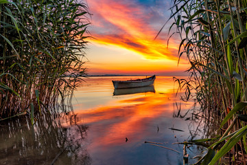 Beautiful morning landscape with a boat on the lake at the sunrise through the reed, Razelm Lake, Razim, Sarichioi, Romania