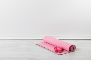 pink fitness mat and dumbbells on floor