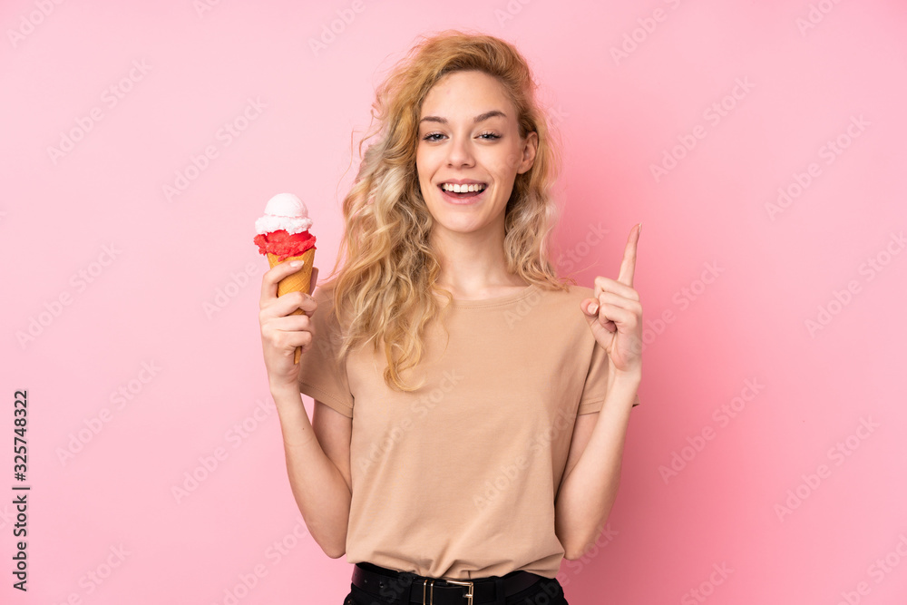 Canvas Prints Young blonde woman holding a cornet ice cream isolated on pink background pointing up a great idea