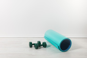 fitness mat and dumbbells on floor at home