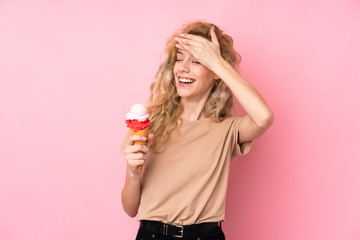 Young blonde woman holding a cornet ice cream isolated on pink background has realized something and intending the solution