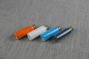 Blue, red, white and indigo powder and crystalls crystals in small bottles on gray linen background