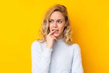 Young blonde woman isolated on yellow background nervous and scared