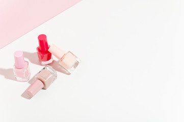 Manicure nail polish in small glass bottles set. Bright red and nude colours of nail-varnish isolated on white and pink background. Unbranded mockup copy space. Professional salon procedure concept