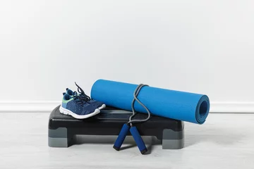 Fototapeten step platform, fitness mat, jump rope and sport shoes on floor at home © LIGHTFIELD STUDIOS