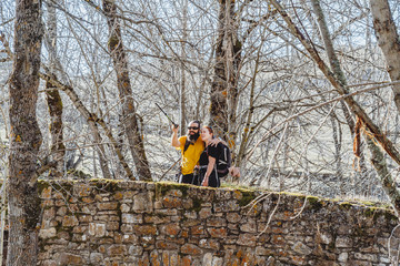 A couple of bearded man and woman with red hair on a stone bridge sightseeing look at the landscape in an environment with trees