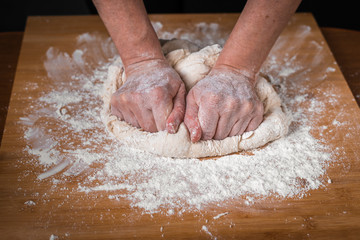 Making dough by female hands on wooden table background close up