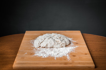 raw dough with flour lies on a wooden Board on the table