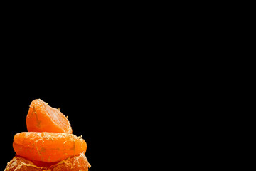 Several slices tangerine on a black background with blank space