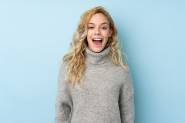 Young blonde woman wearing a sweater isolated on blue background with surprise facial expression