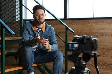 Young blogger recording video on camera indoors