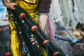 Mains d'un pêcheur en train de ranger ses filets de pêche - obrazy, fototapety, plakaty