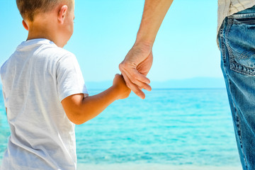 happy dad holds the hand of a child by the greek sea in nature