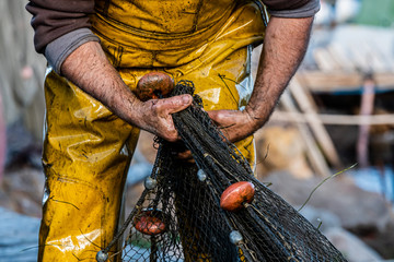 Mains d'un pêcheur en train de ranger ses filets de pêche
