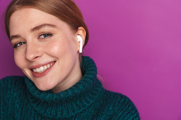 Photo of smiling caucasian woman using wireless earphone