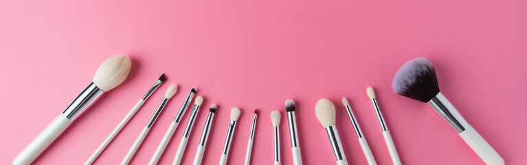 white makeup brushes on a pink background