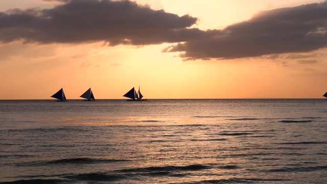 Paraw sailing boats during golden sunset at Boracay Island - Philippines
