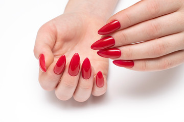 Red manicure on long sharp nails closeup on a white background. Red stilettos. Gel nails. - obrazy, fototapety, plakaty