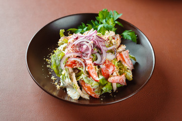 Vegetable salad with sauce in a plate on a brown table