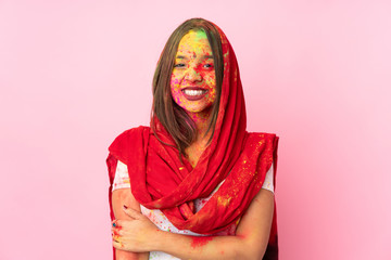 Young Indian woman with colorful holi powders on her face isolated on pink background laughing