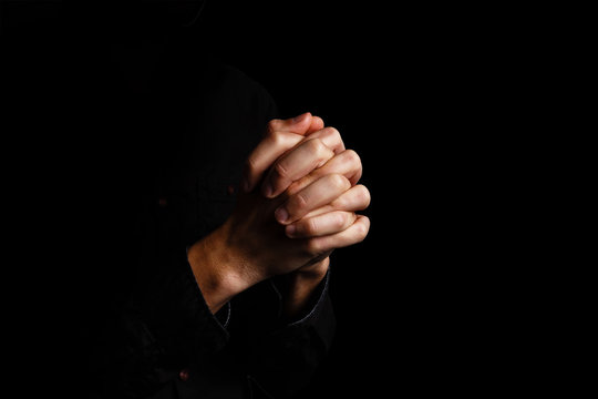 Image of praying hands on a black background