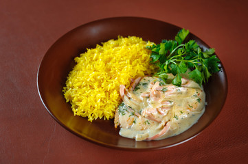 Pork in rice and herbs sauce in a plate on a brown table