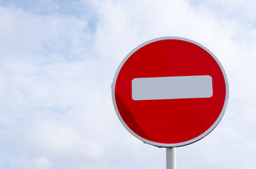 no entry road sign on sky background with clouds
