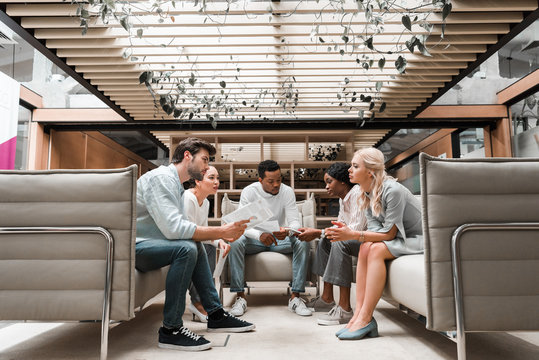 Young Multicultural Businesspeople Sitting In Office Lounge During Meeting