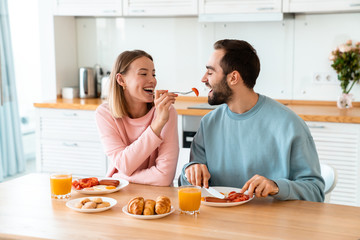 Portrait of young happy couple eating together while having breakfast