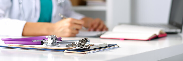 Stethoscope head lying on medical forms on clipboards closeup