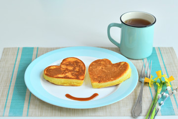 Two american pancakes on blue plate for healthy breakfast on wooden table.Breakfast on Valentine's Day or 8 March - pancakes in the shape of a heart.