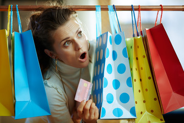 woman peeking out from shopping bags with red credit card