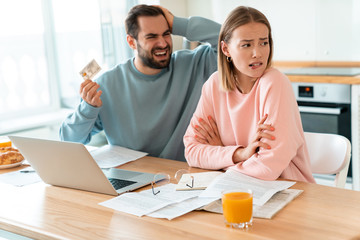 Portrait of annoyed couple having argument while holding credit card