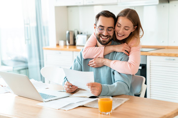 Obraz premium Portrait of smiling couple hugging while working with documents